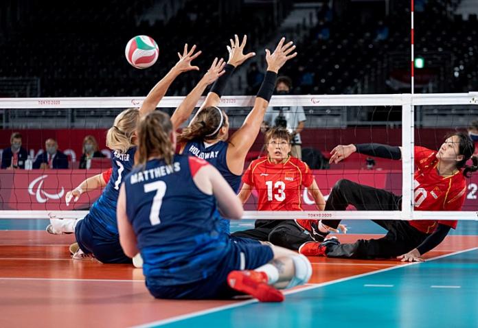 Yixiao Xu tries to get the ball over the net, while her opponent blocks.